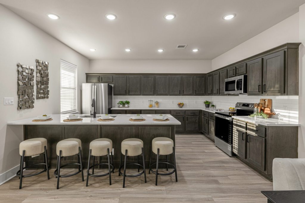Kitchen at The Barracks with dark wood cabinetry, a large quartz island and bar seating for five.