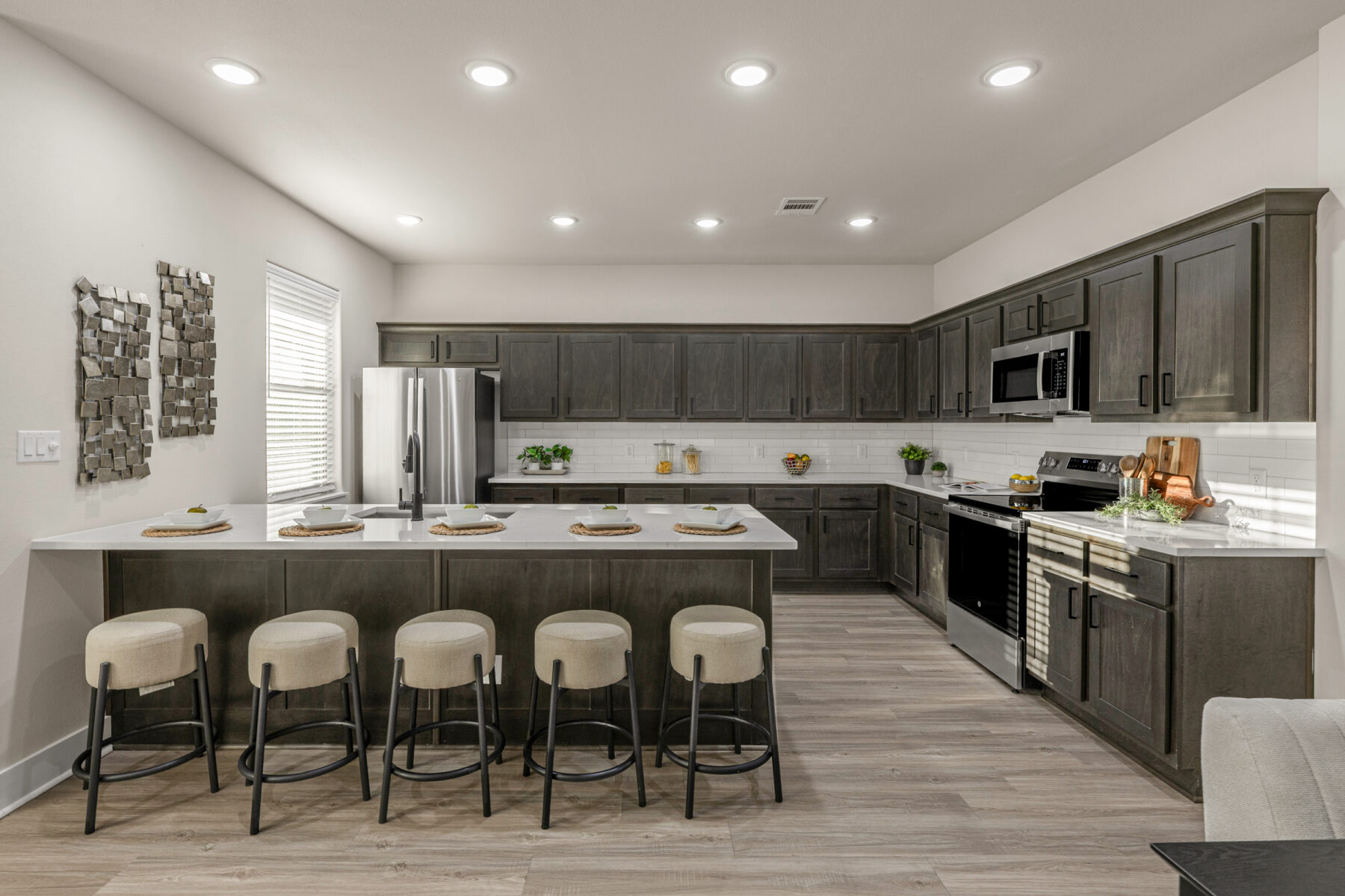 Kitchen at The Barracks with dark wood cabinetry, a large quartz island and bar seating for five.