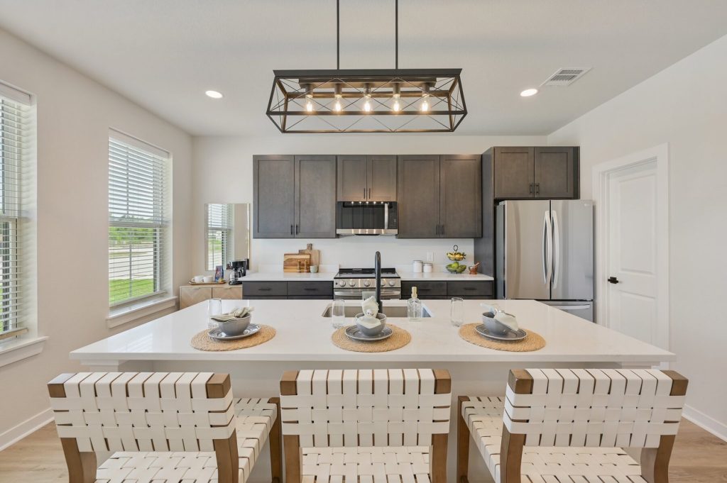 Kitchen at Charleston Mills College Station with wood cabinetry, a large island and bar seating for three.