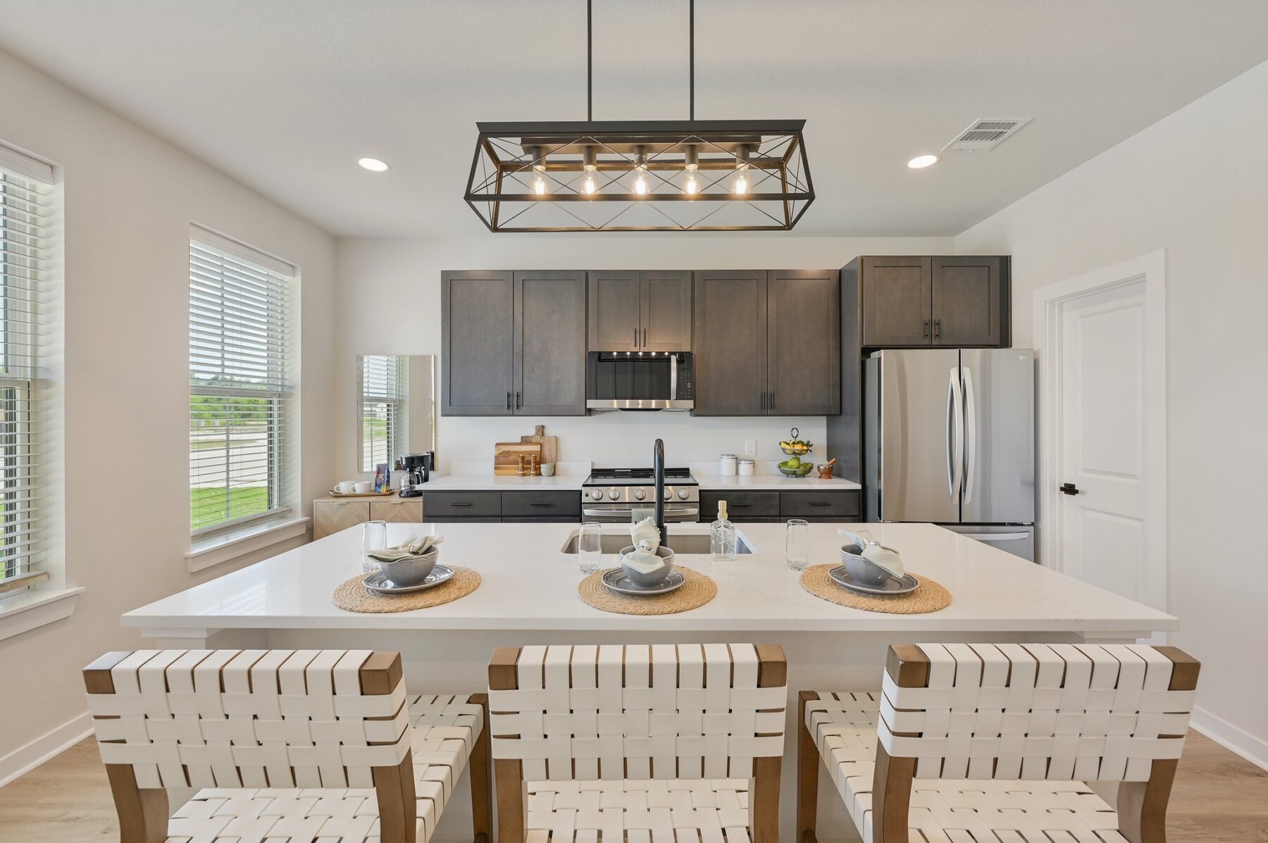 Kitchen at Charleston Mills College Station with wood cabinetry, a large island and bar seating for three.