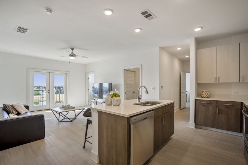 Open-concept living room and kitchen at The Harbor, featuring a quartz island, stainless steel appliances and a private balcony.