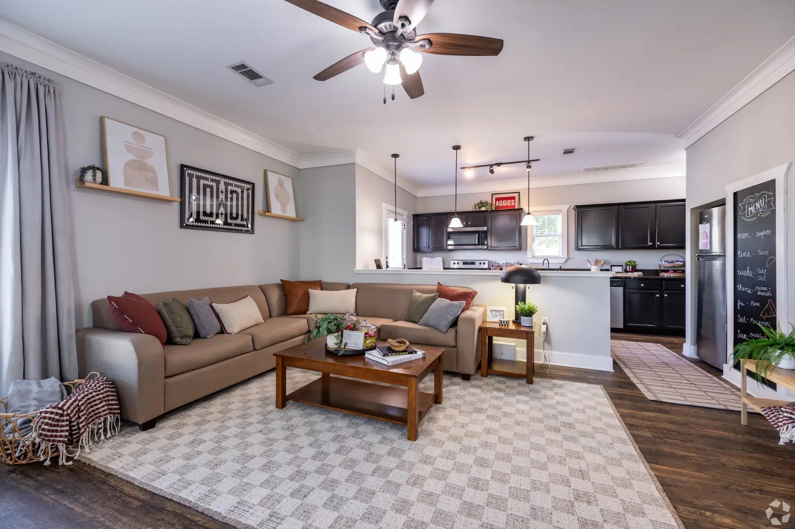Open-concept living room and kitchen inside a furnished cottage-style apartment at The Cottages of College Station.