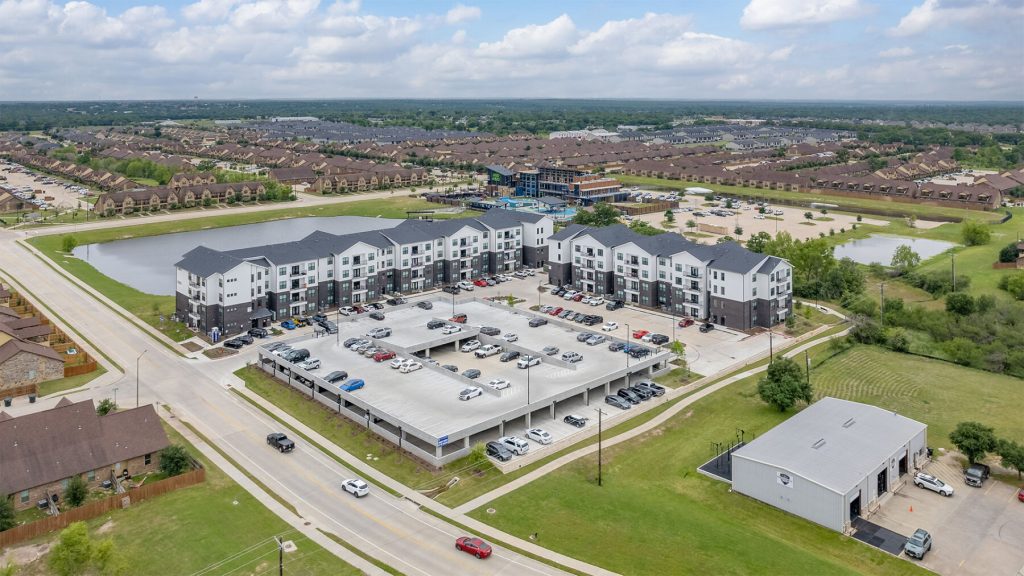 Aerial view of The Harbor at The Barracks, showing the apartment buildings, parking garage and surrounding College Station neighborhood.