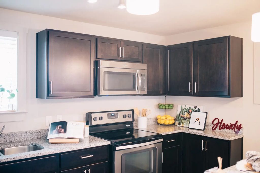 Modern kitchen at The Junction at College Station with granite countertops, dark cabinetry and stainless steel appliances.